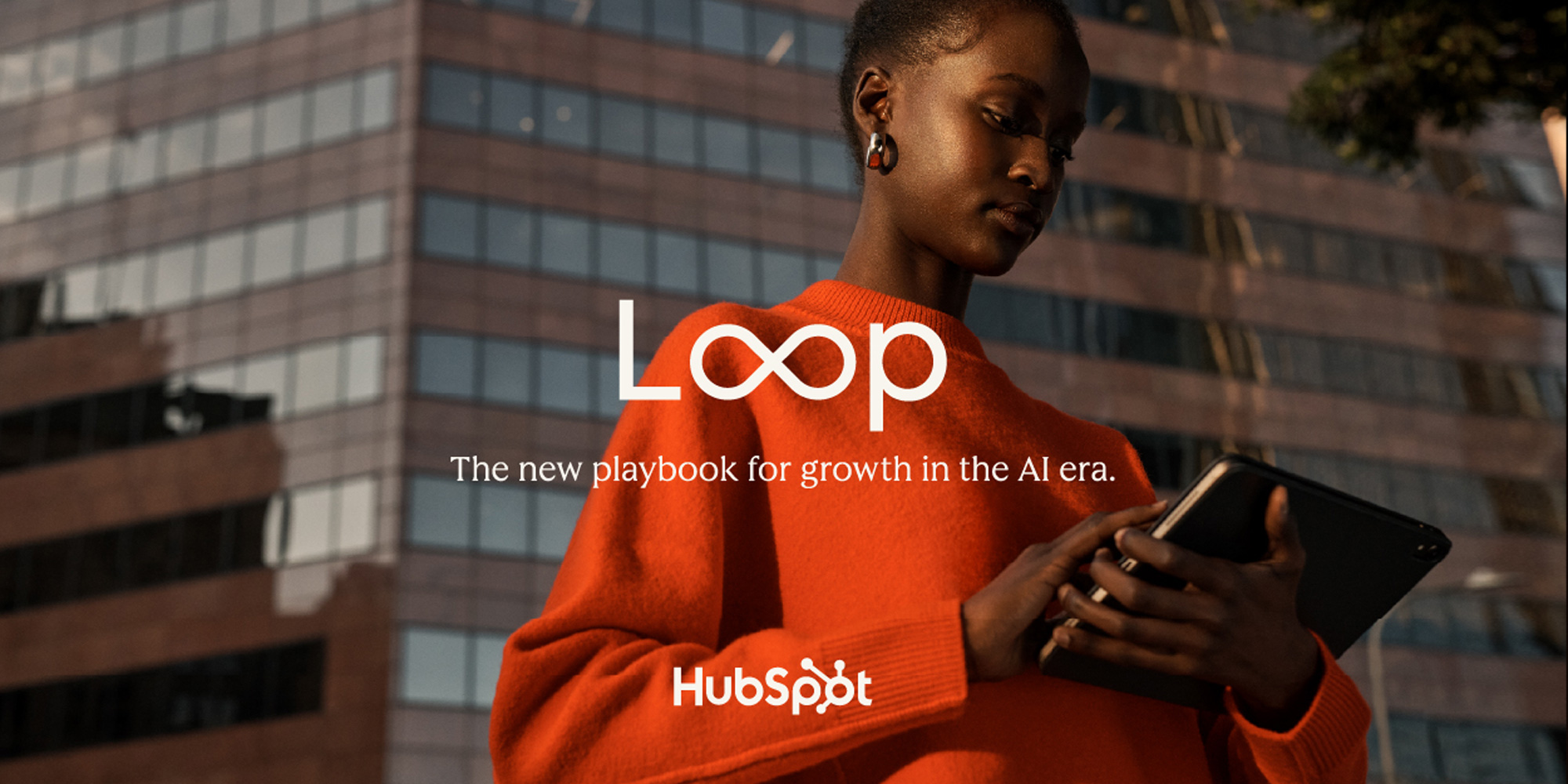 Woman wearing bright orange sweater on her phone. HubSpot Loop.